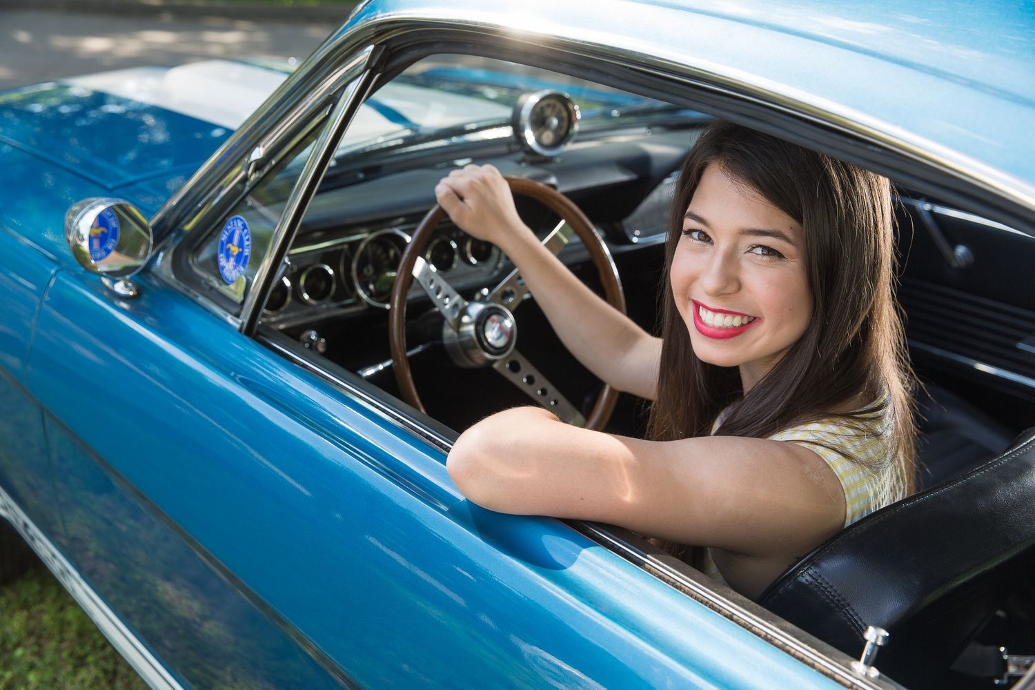Classic blue car photographed during sunset with driver visible through window.