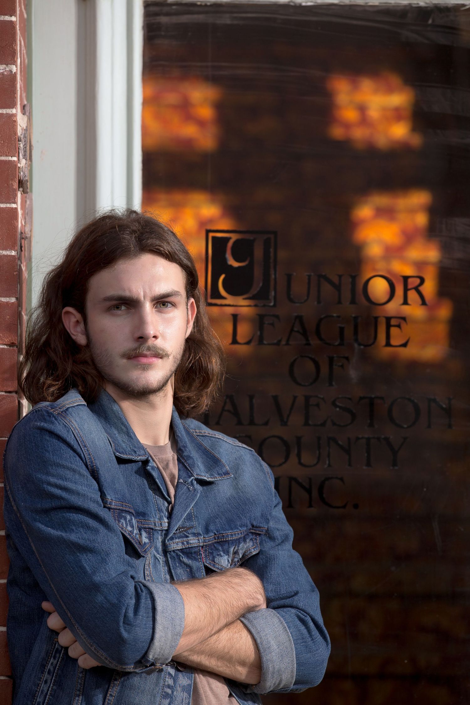 Portrait against brick wall with Junior League of Galveston County signage.