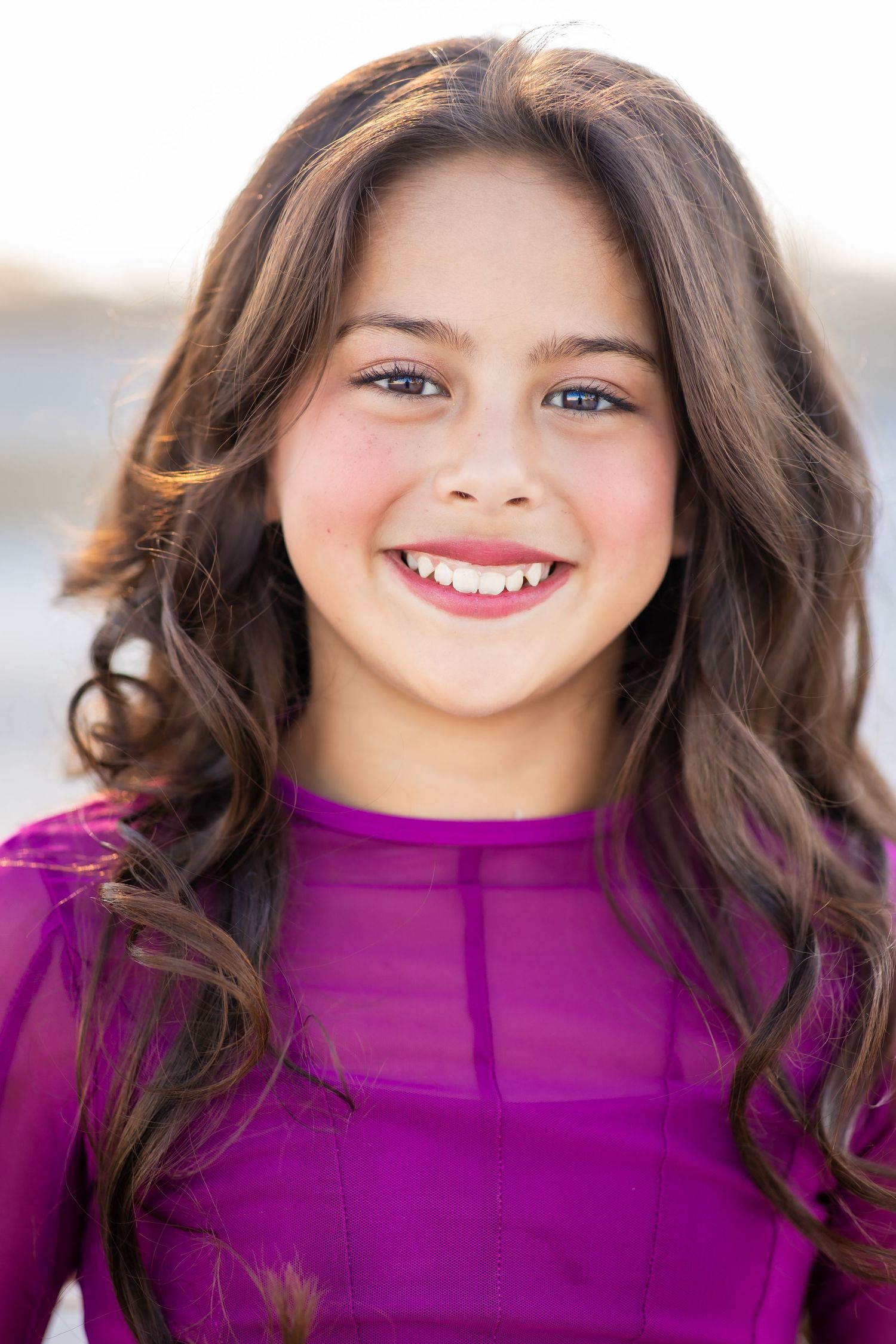Portrait in vibrant purple top with natural lighting and warm expression.