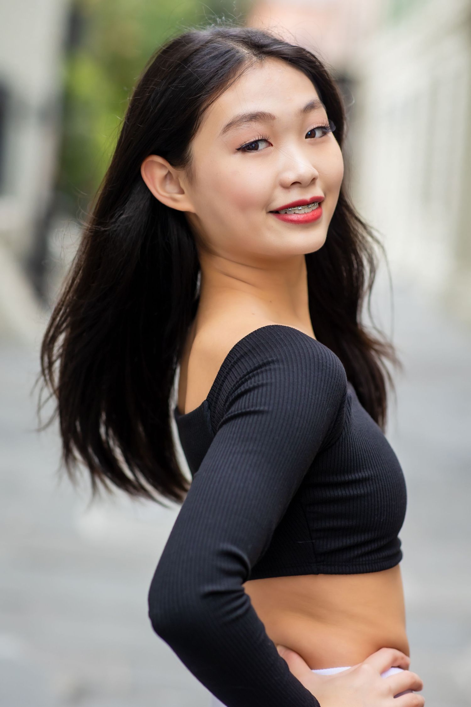 Athletic dancer in black crop top poses against urban background.