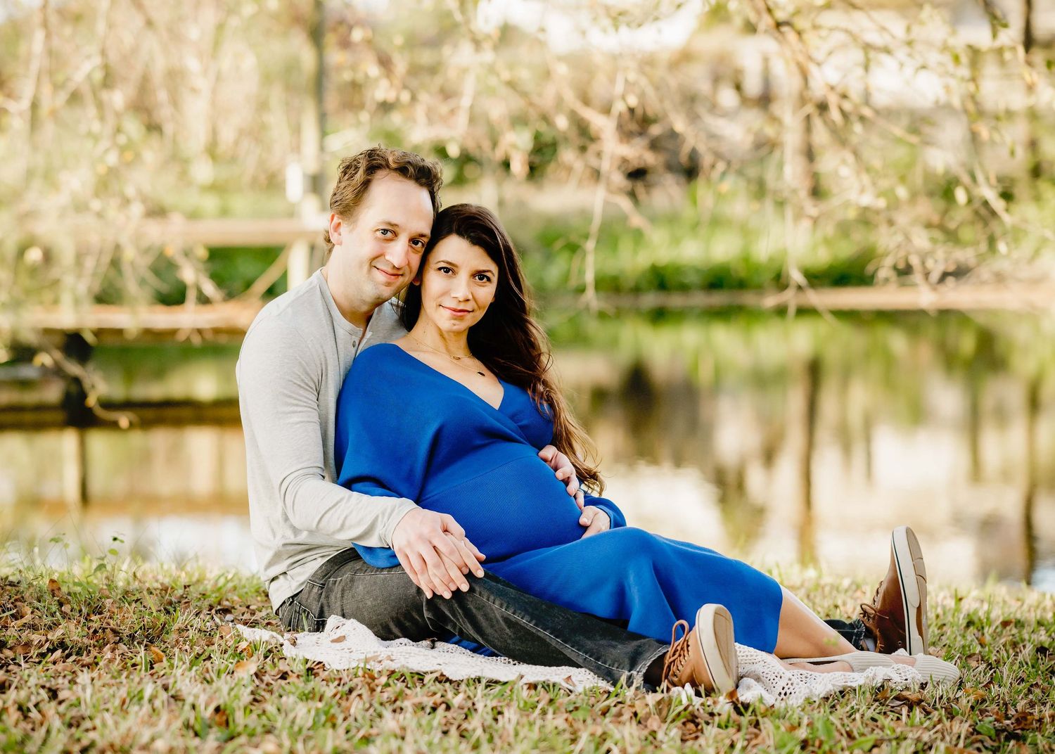 Maternity photoshoot in a serene outdoor setting with spring blossoms and natural light.