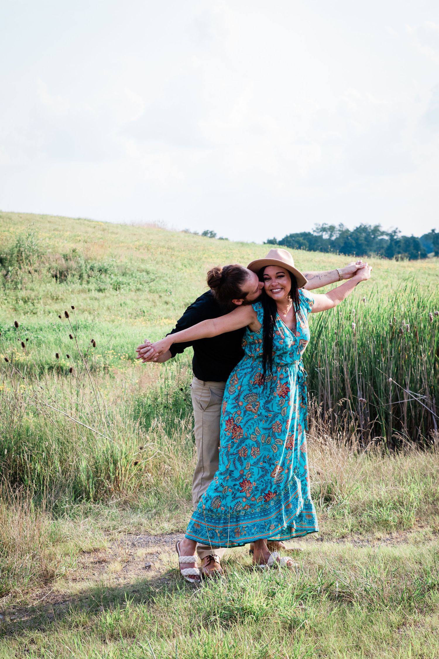 Boho Chic Hat Engagement Photo Kissing in a field airplane arms