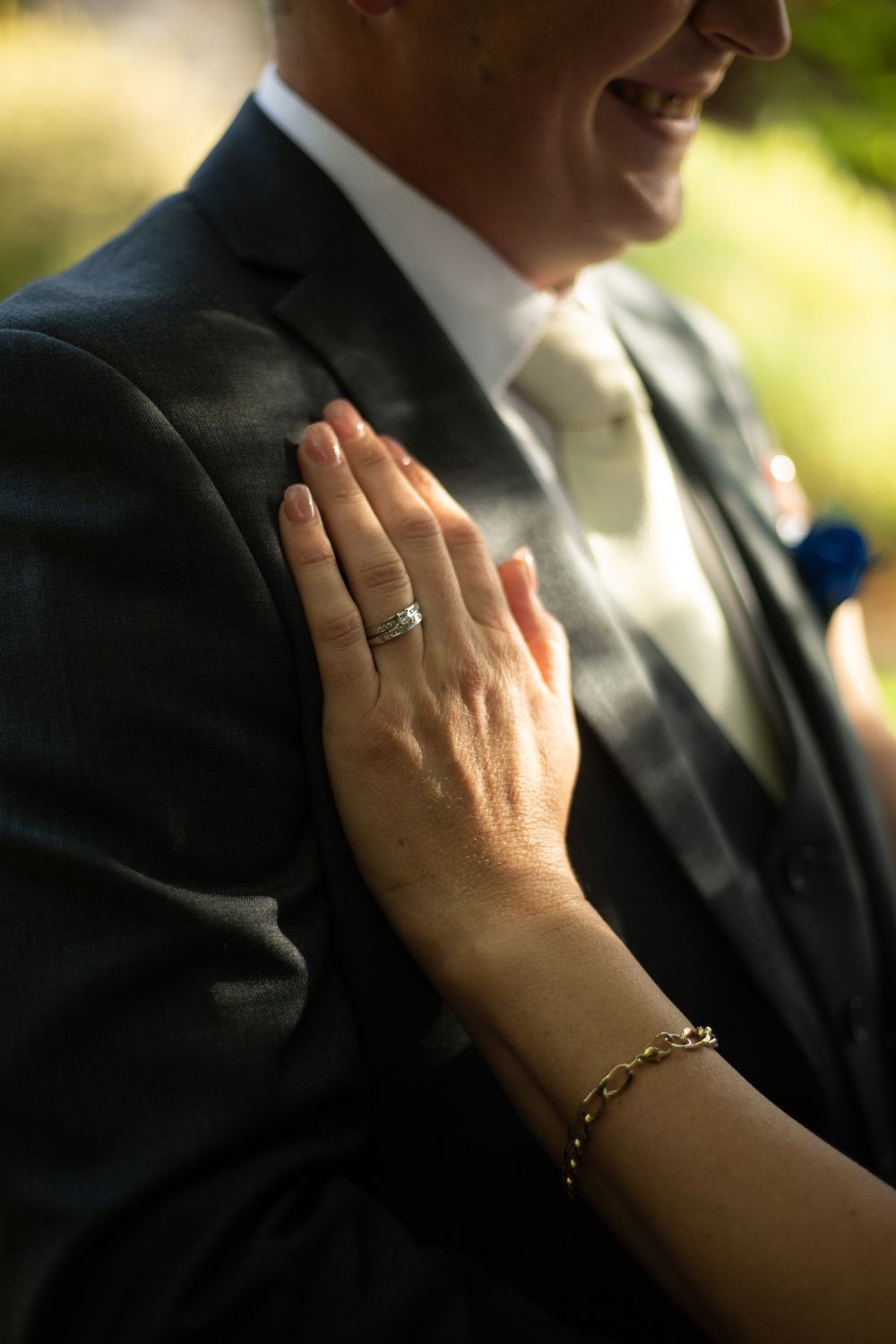 brides hand with wedding rings on display holding her husbands chest