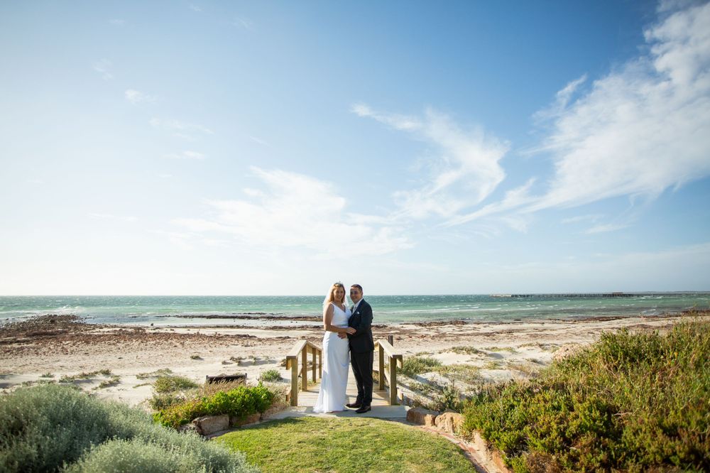 bride and groom holding each other on jetty overlooking beach at Kemp Place in Moonta Bay