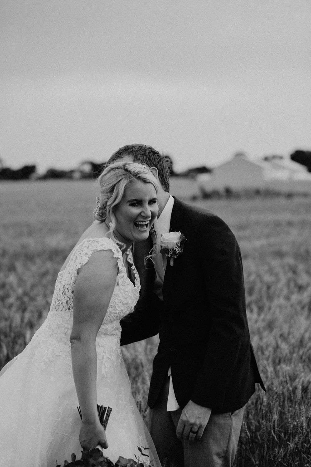bride in black and white laughing with her groom in a farm