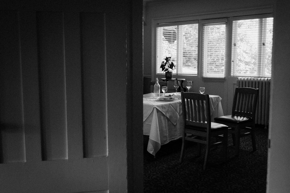 Two empty chairs face each other next to a small round dining table. A wedding dinner took place.