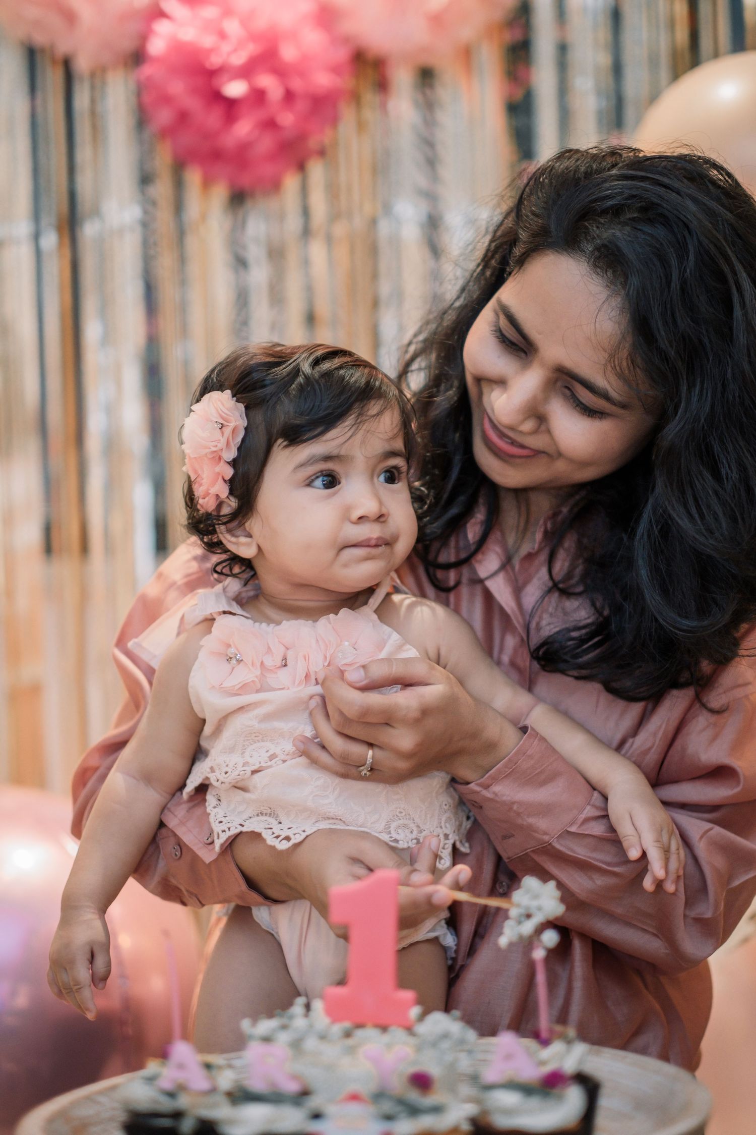 First birthday celebration with pink decor and a decorated cake.