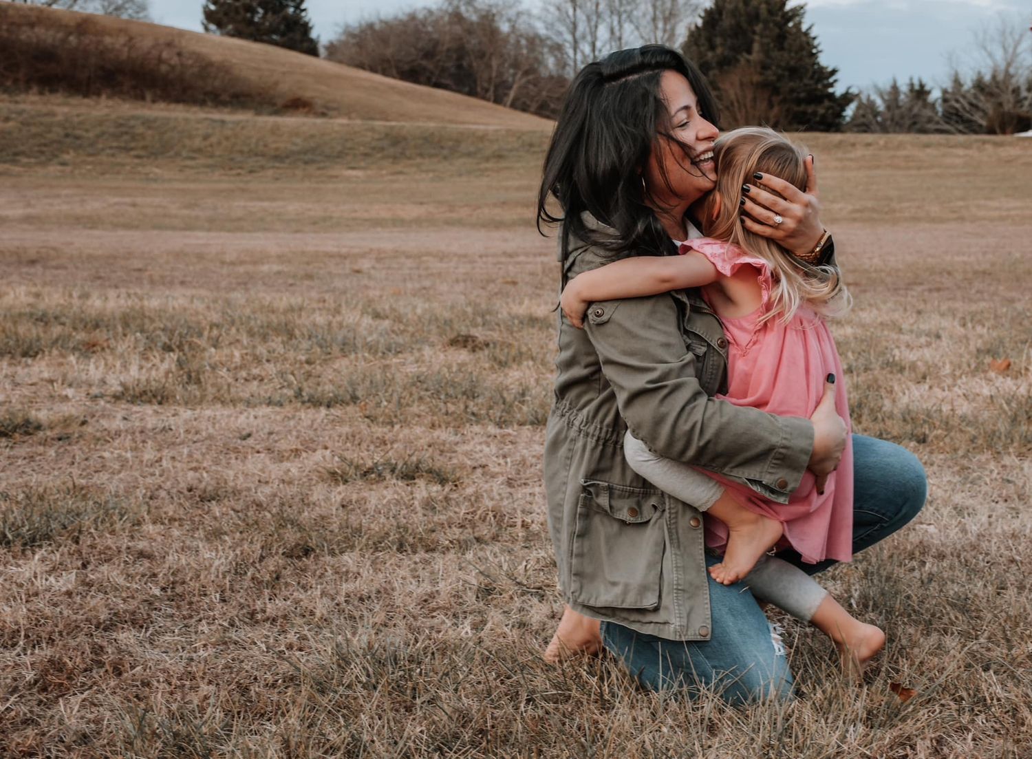 Mother and daughter in field hugging for mommy and me session. Captured by Maryland Photographer Mallory Bramlett.