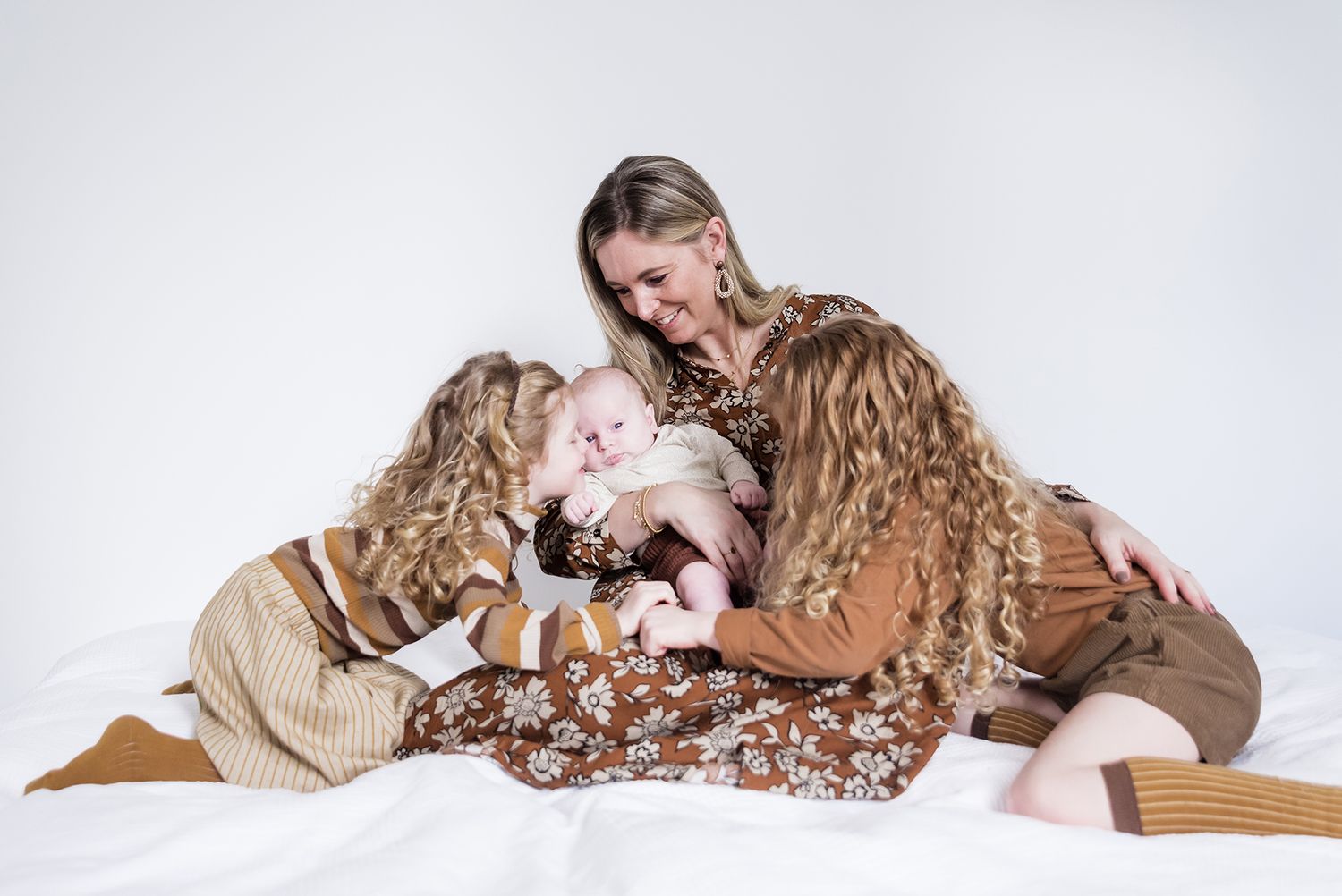 Studio portrait showing tender family moment in earth-toned clothing.