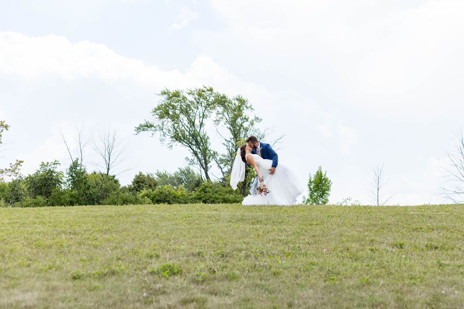 bride and groom dip on a hill