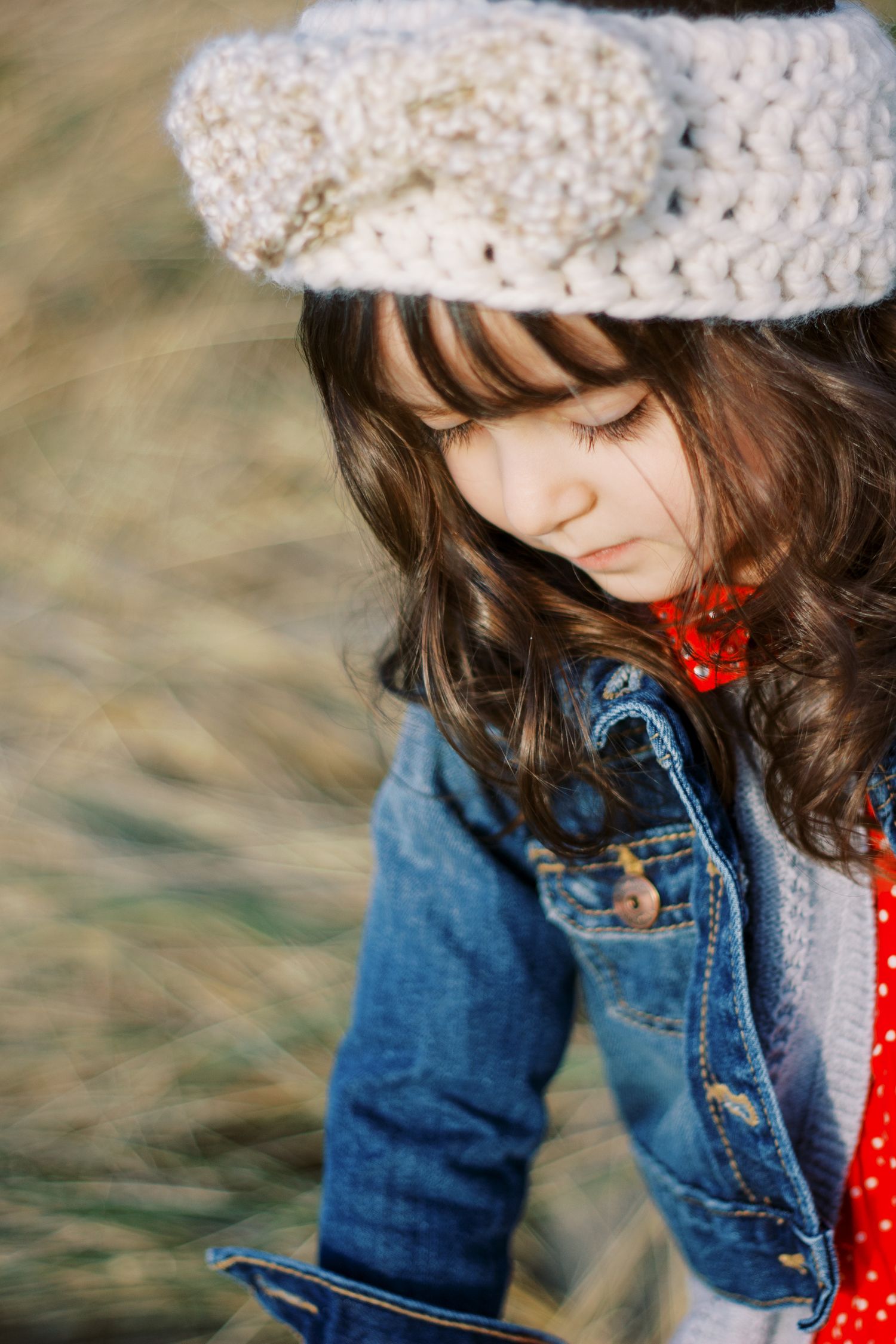 Close up view of a knit hat, denim jacket and red polka dot dress ensemble.
