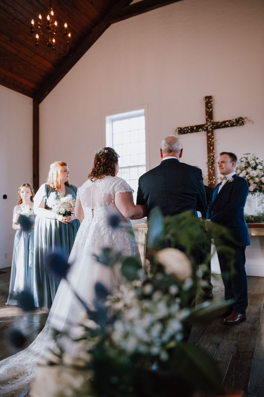 Wedding ceremony sequence showing guests gathered in a bright white chapel room with a rustic wooden cross.