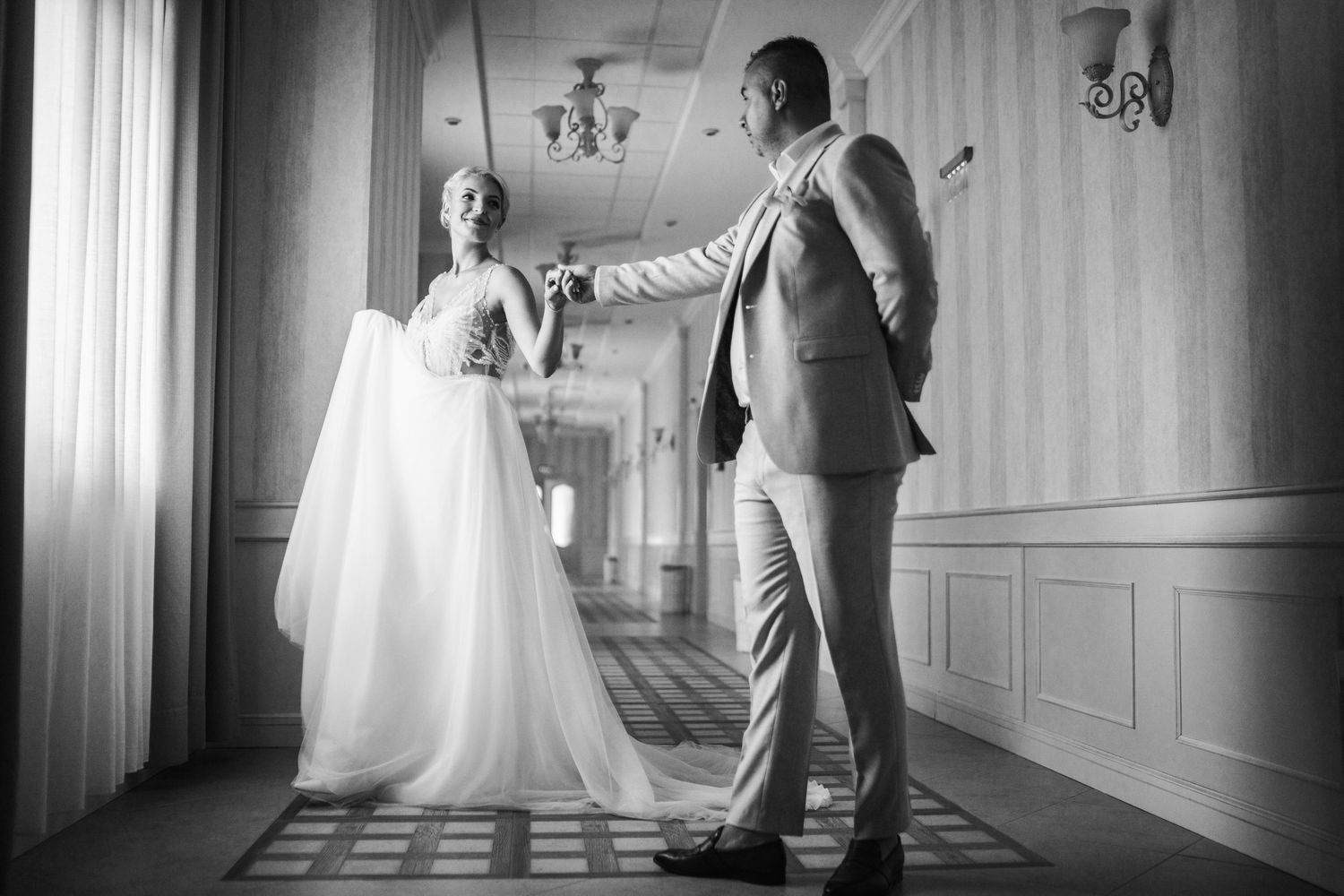 A couple shares their first look moment in an elegant hallway before their wedding ceremony.