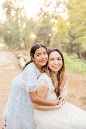 Outdoor portrait session in a sunlit natural setting with white lace dresses.