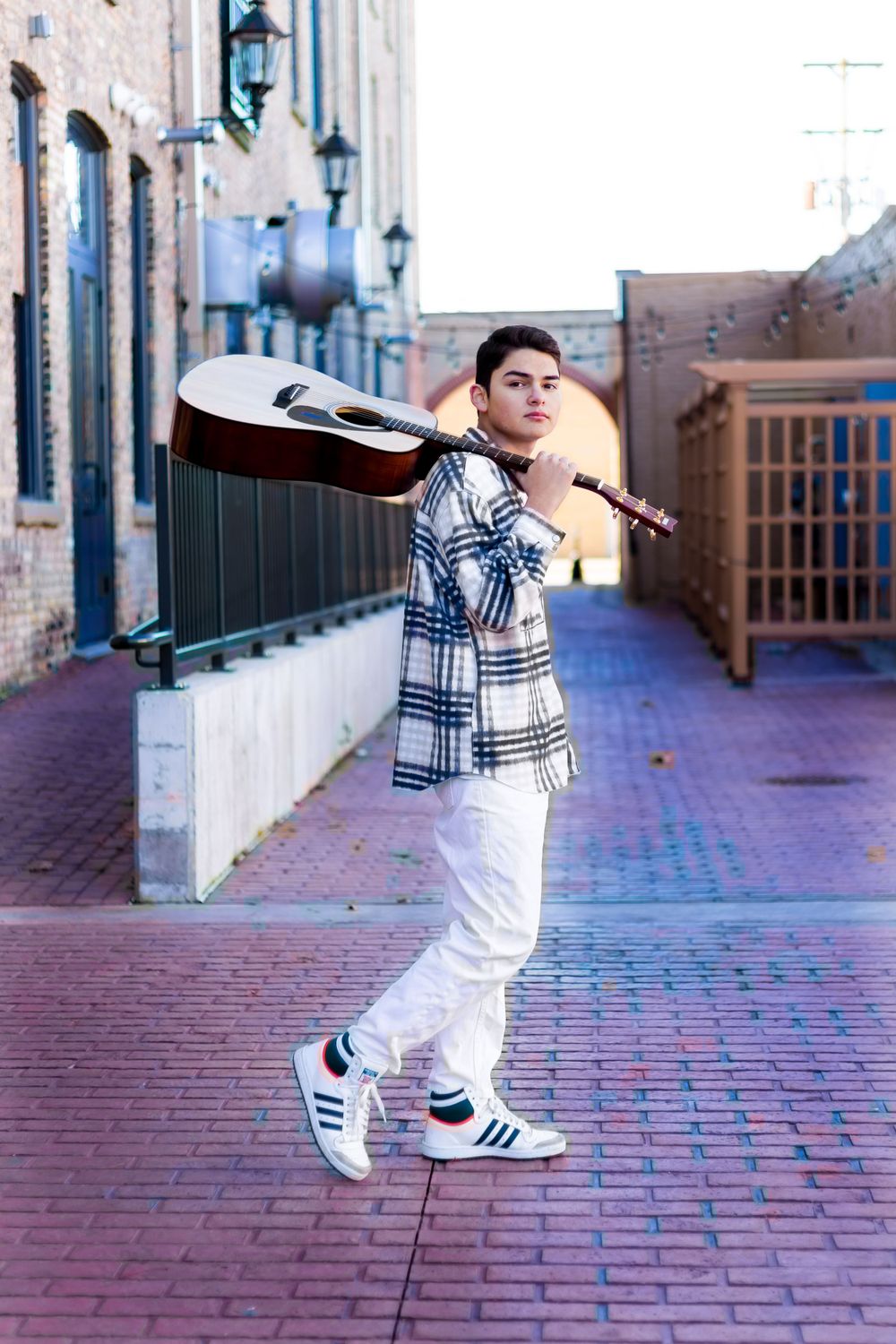 Male high School Senior carrying a guitar