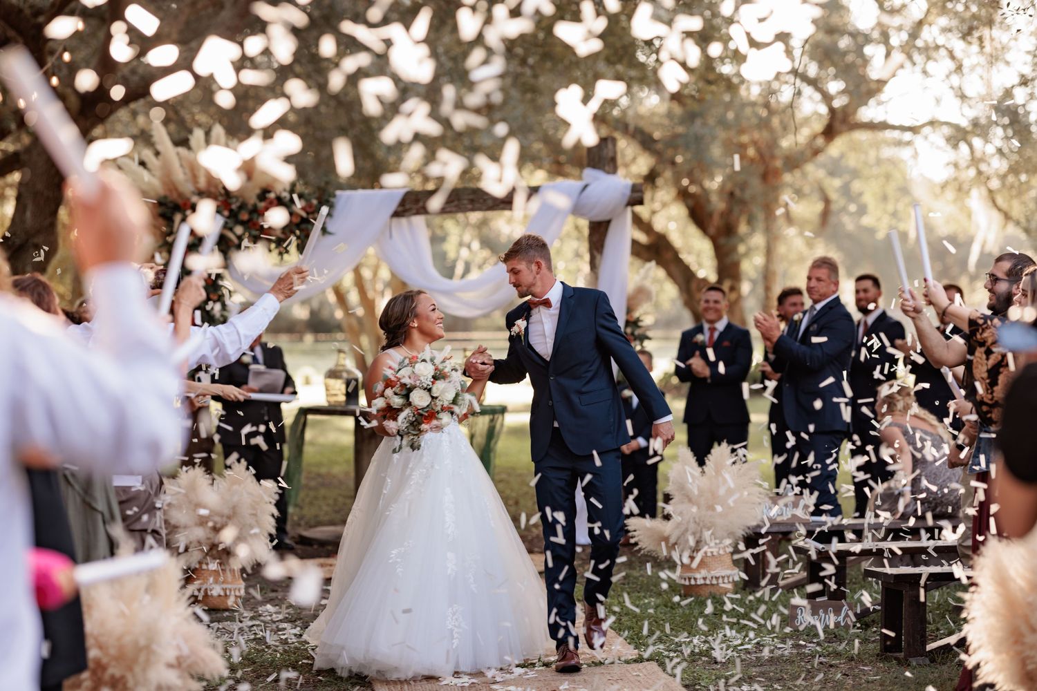 Wedding celebration with confetti being thrown at sunset in garden setting.