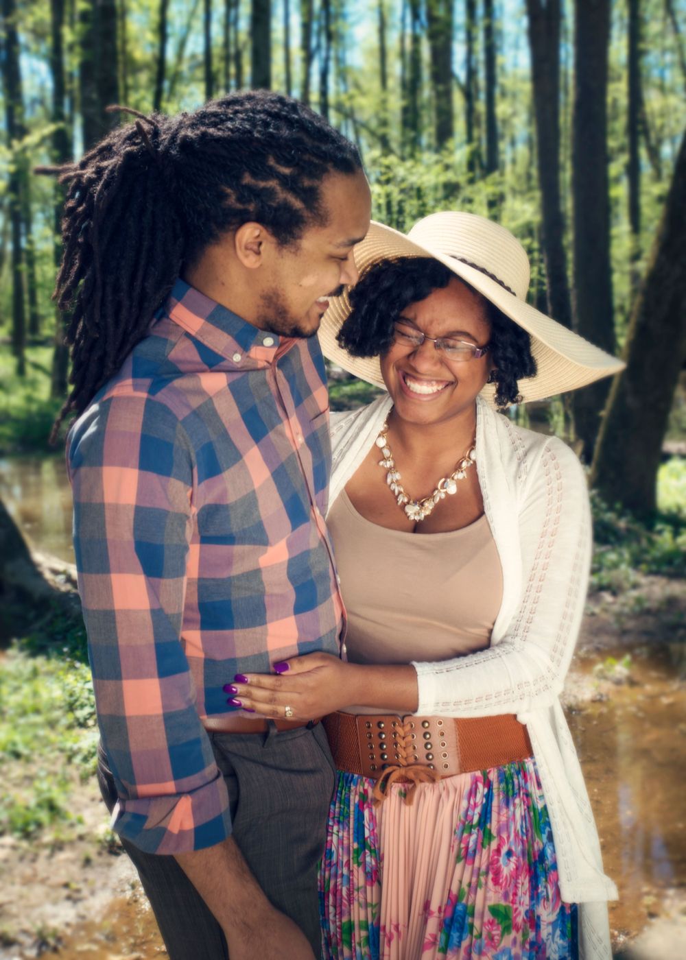 Romantic couple sharing a joyful moment while walking in a sunlit forest.