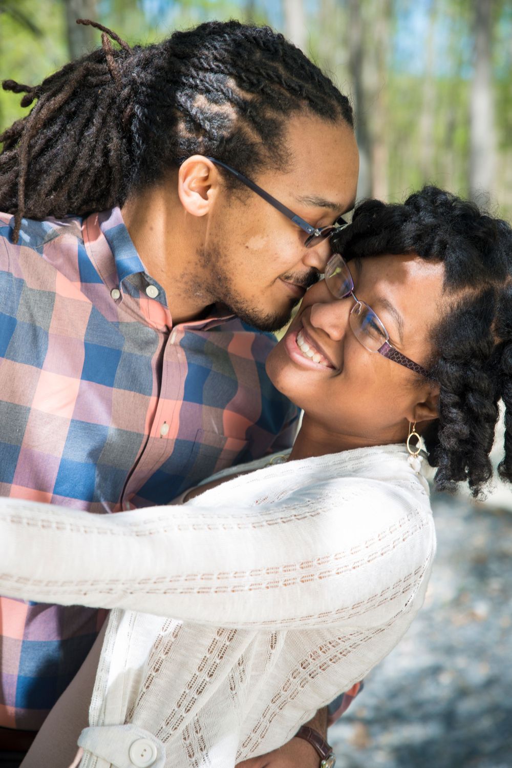 Close-up of affectionate couple laughing and embracing in nature setting.