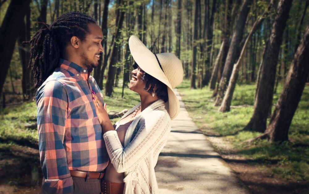 Romantic forest photoshoot with couple on wooded path wearing casual and vintage attire.