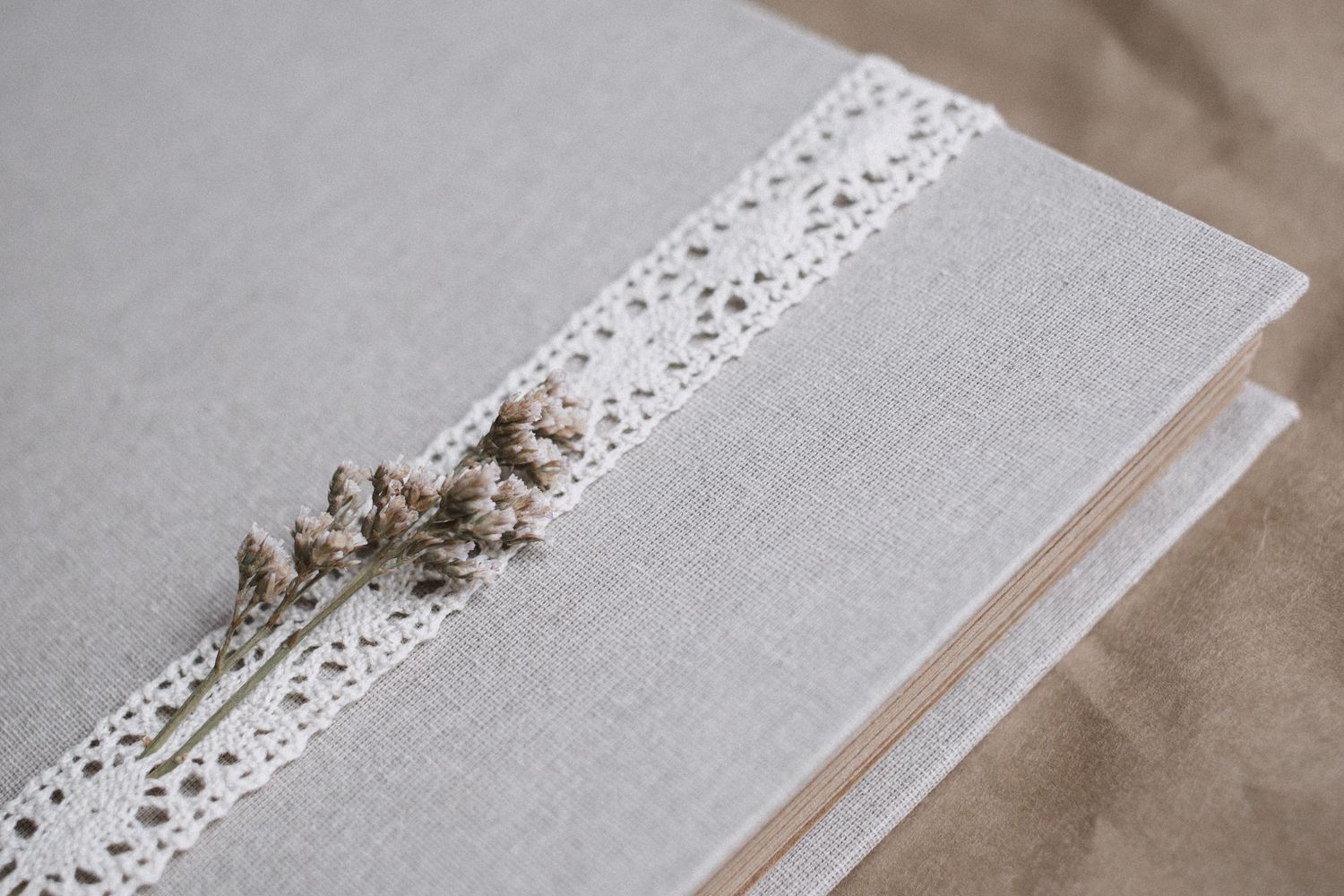 Wedding album with delicate lace detail trim on light gray background.