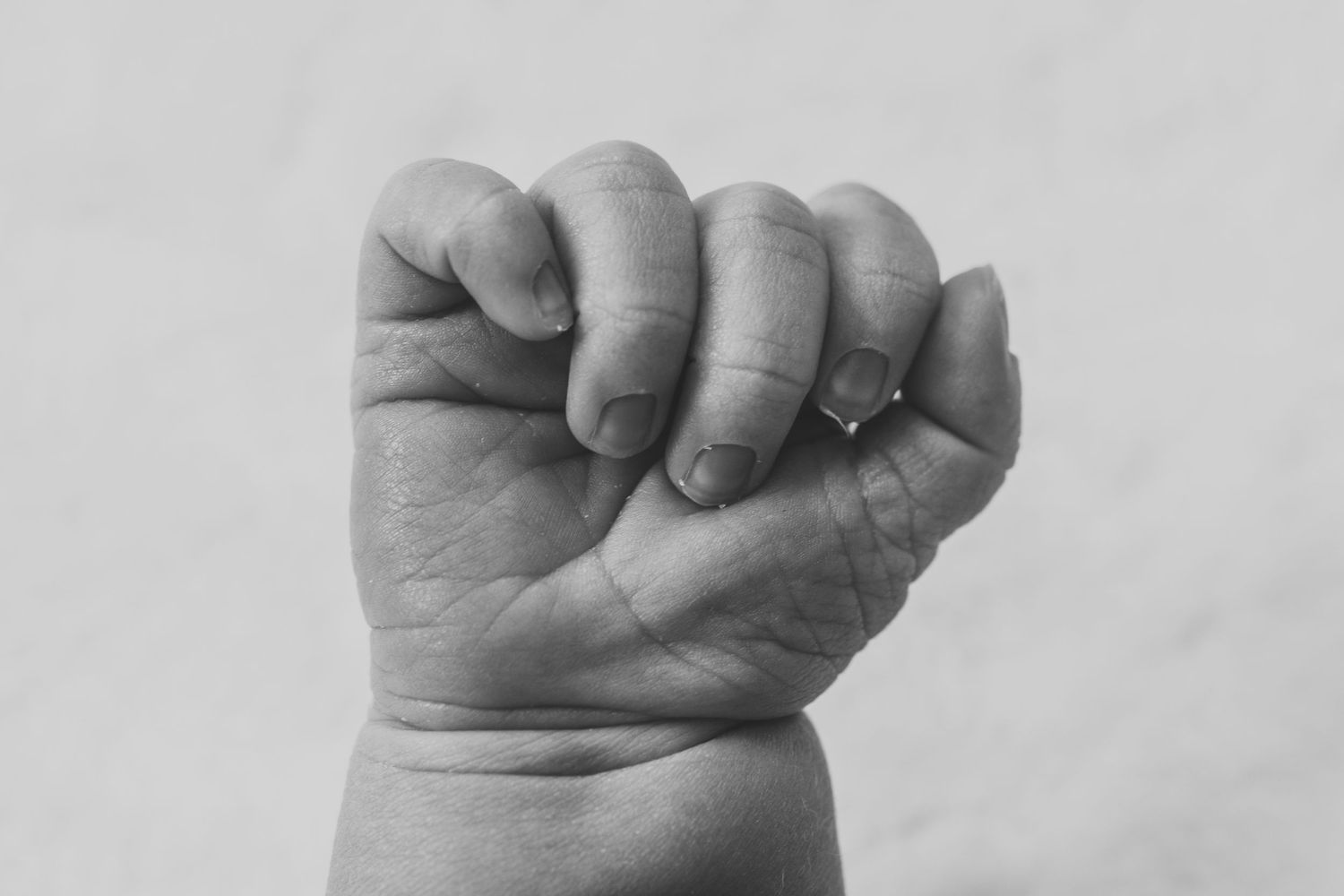 Black and white close-up photograph of a baby's tiny clenched fist.