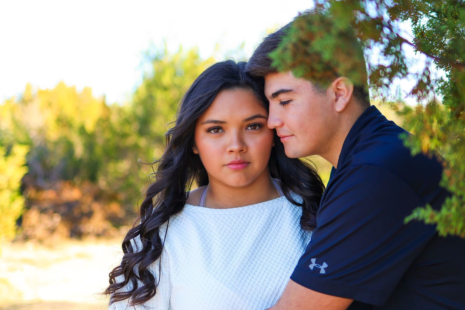 Young couple sharing an intimate moment outdoors in warm sunlight.