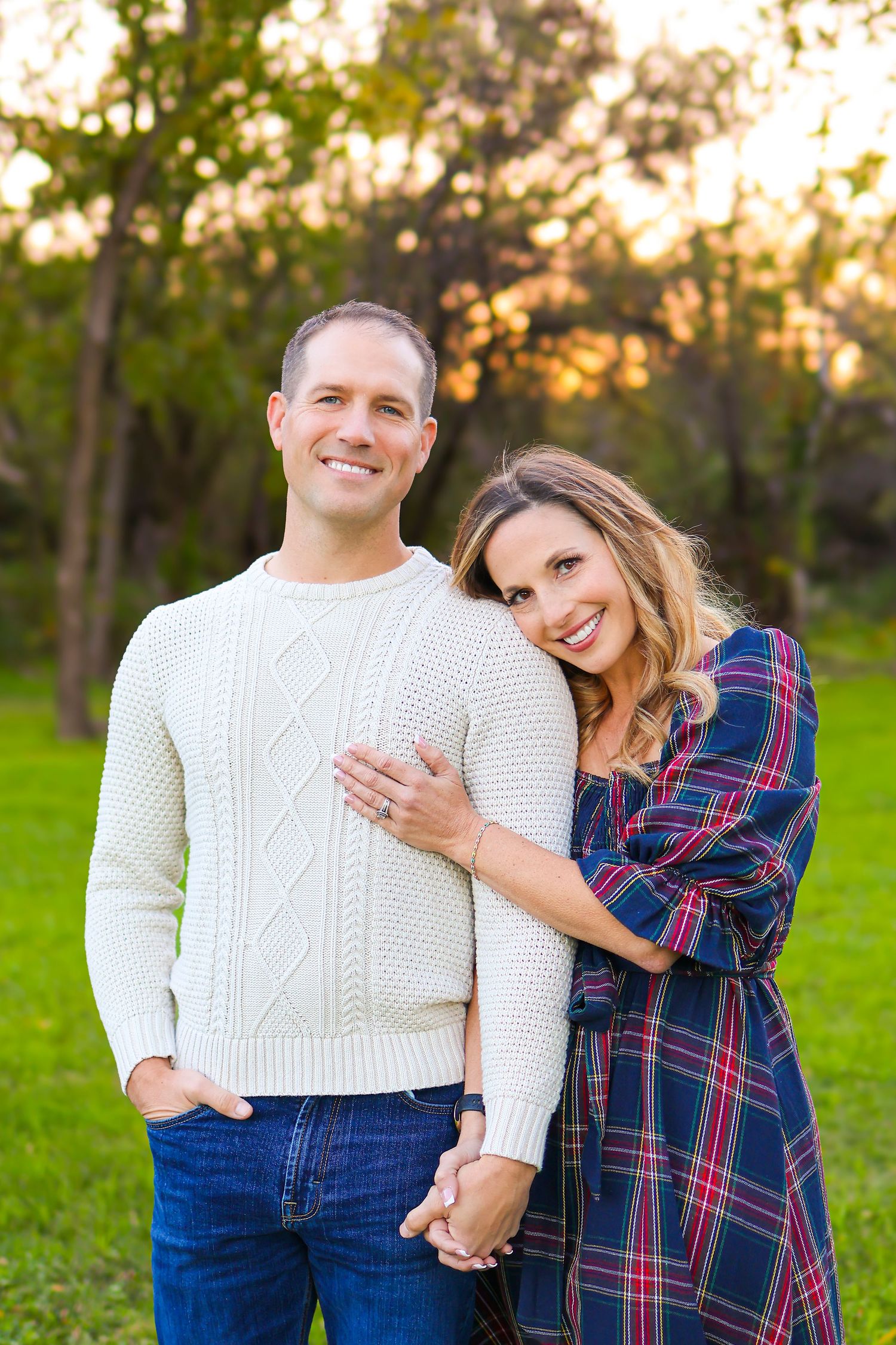 Couple in casual winter wear embracing while posing outdoors in nature.
