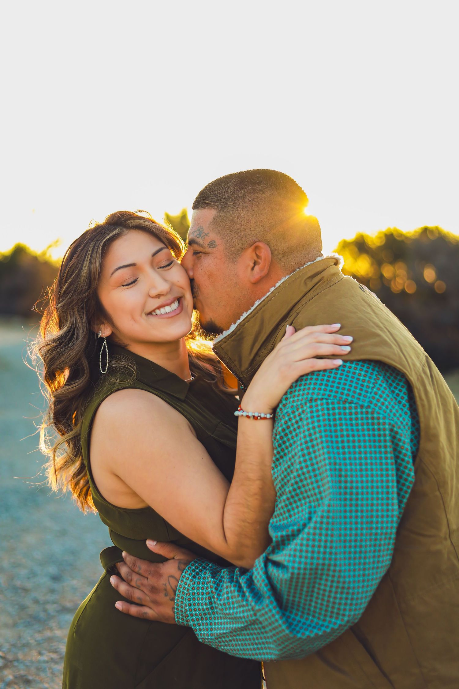 A couple embraces in warm sunset light while sharing an intimate moment outdoors.