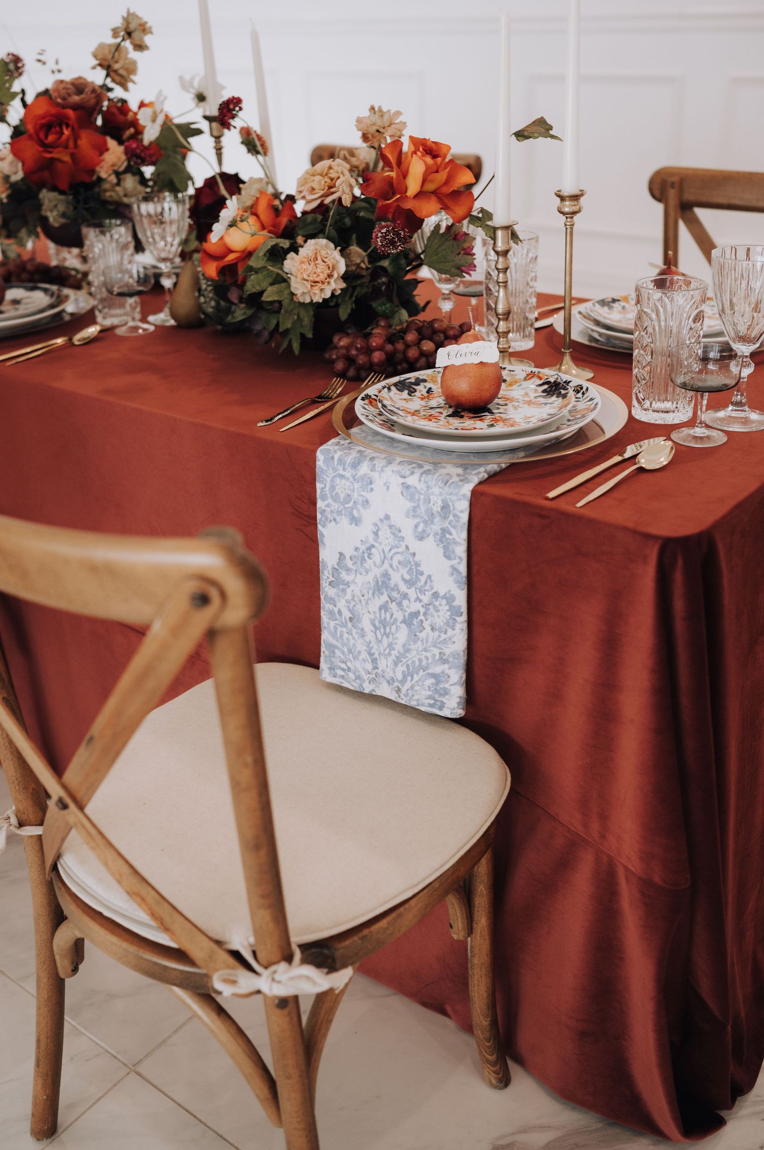 Romantic table setting with burgundy tablecloth, crystal glasses and vibrant autumn floral centerpiece.