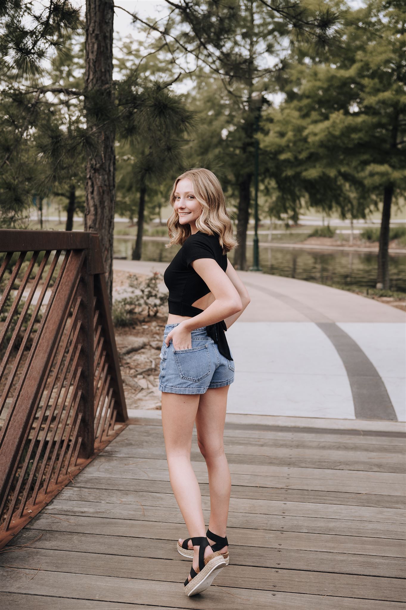 A casual portrait on a wooden bridge in a peaceful park setting.