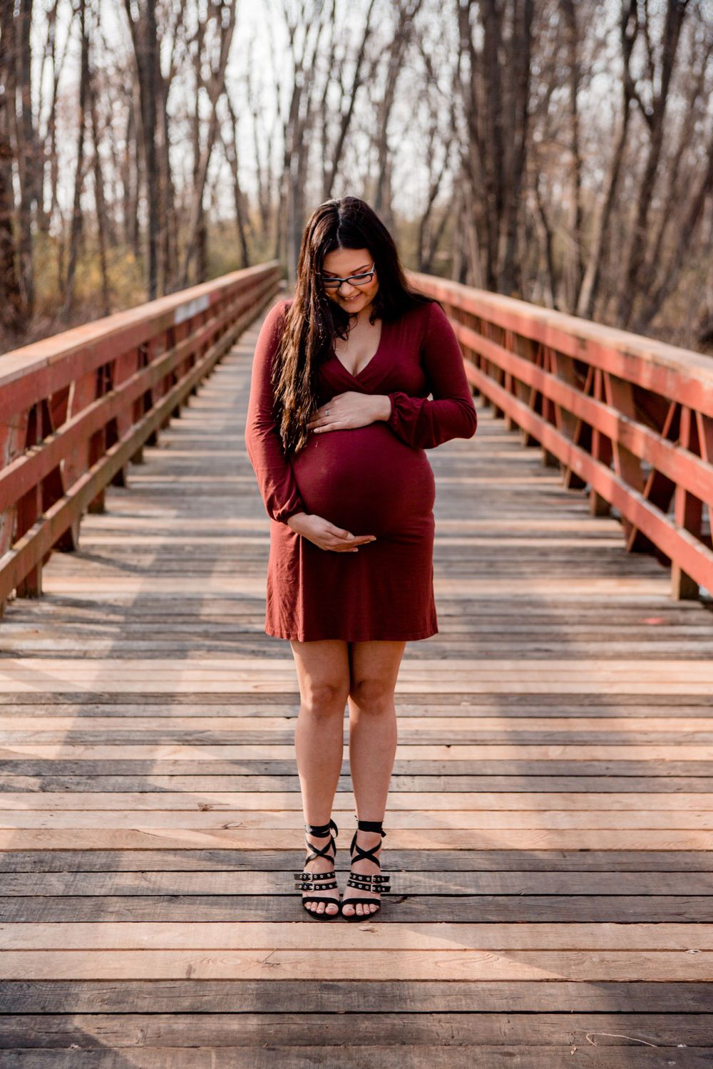 A maternity photo taken on a rustic wooden bridge during fall.