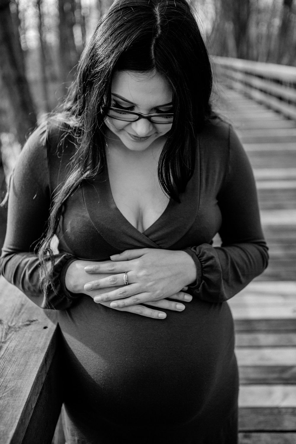 A black and white maternity portrait taken on a wooden bridge.