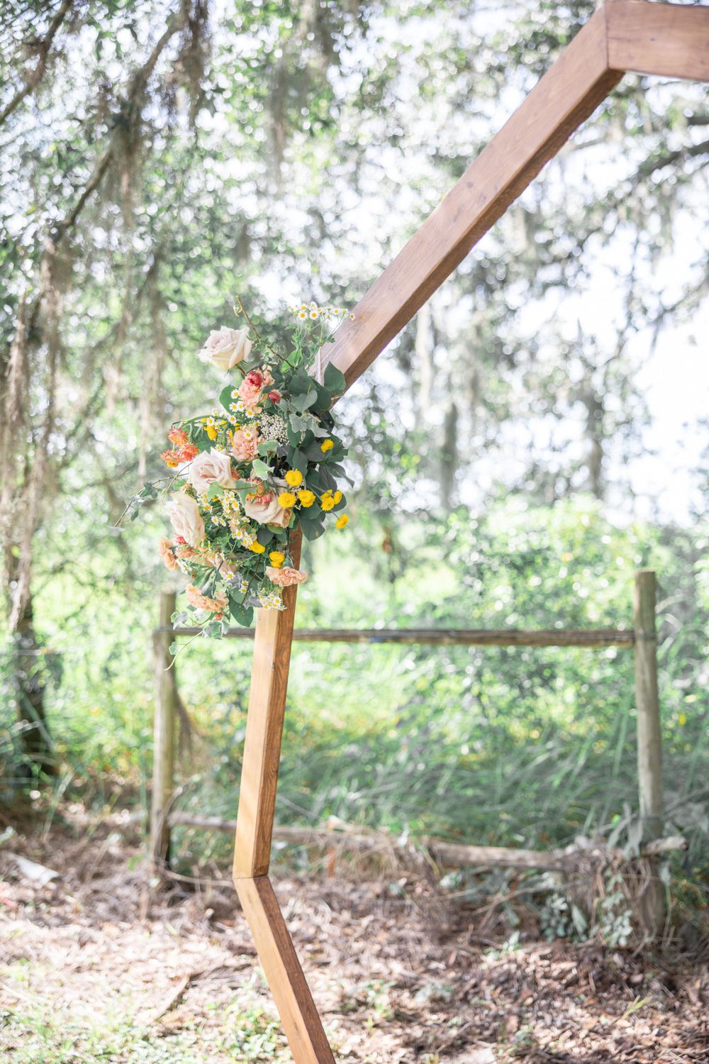 Wedding arch adorned with vibrant yellow, pink, and green flowers at Happy Hearts Barn in Plant City, FL.
