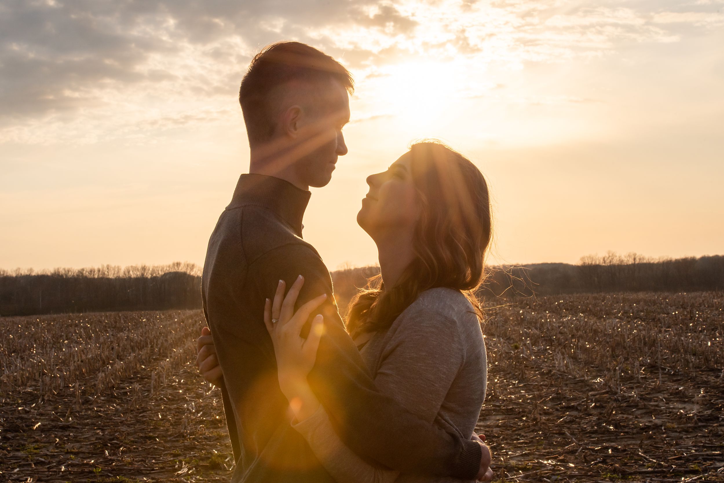 Romantic sunset photoshoot in a golden field with dramatic sky.