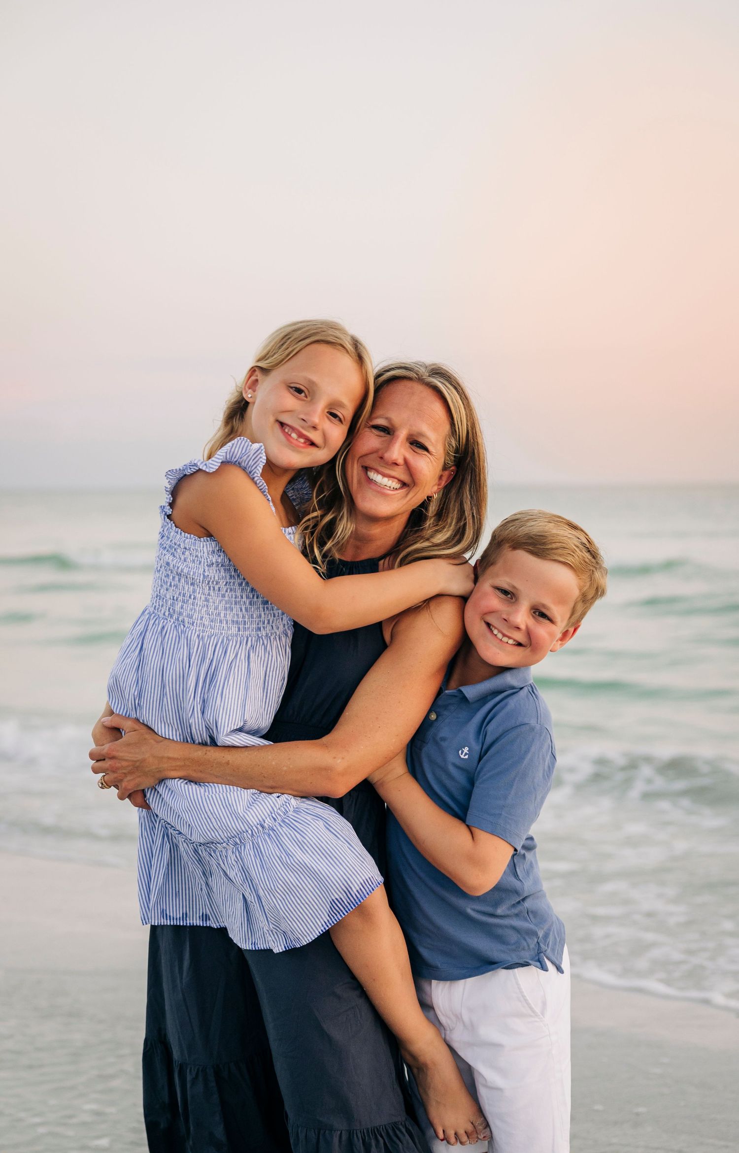 Family smiling happily together on the shore of Siesta Key Beach at sunset taken by Siesta Key Photographer.