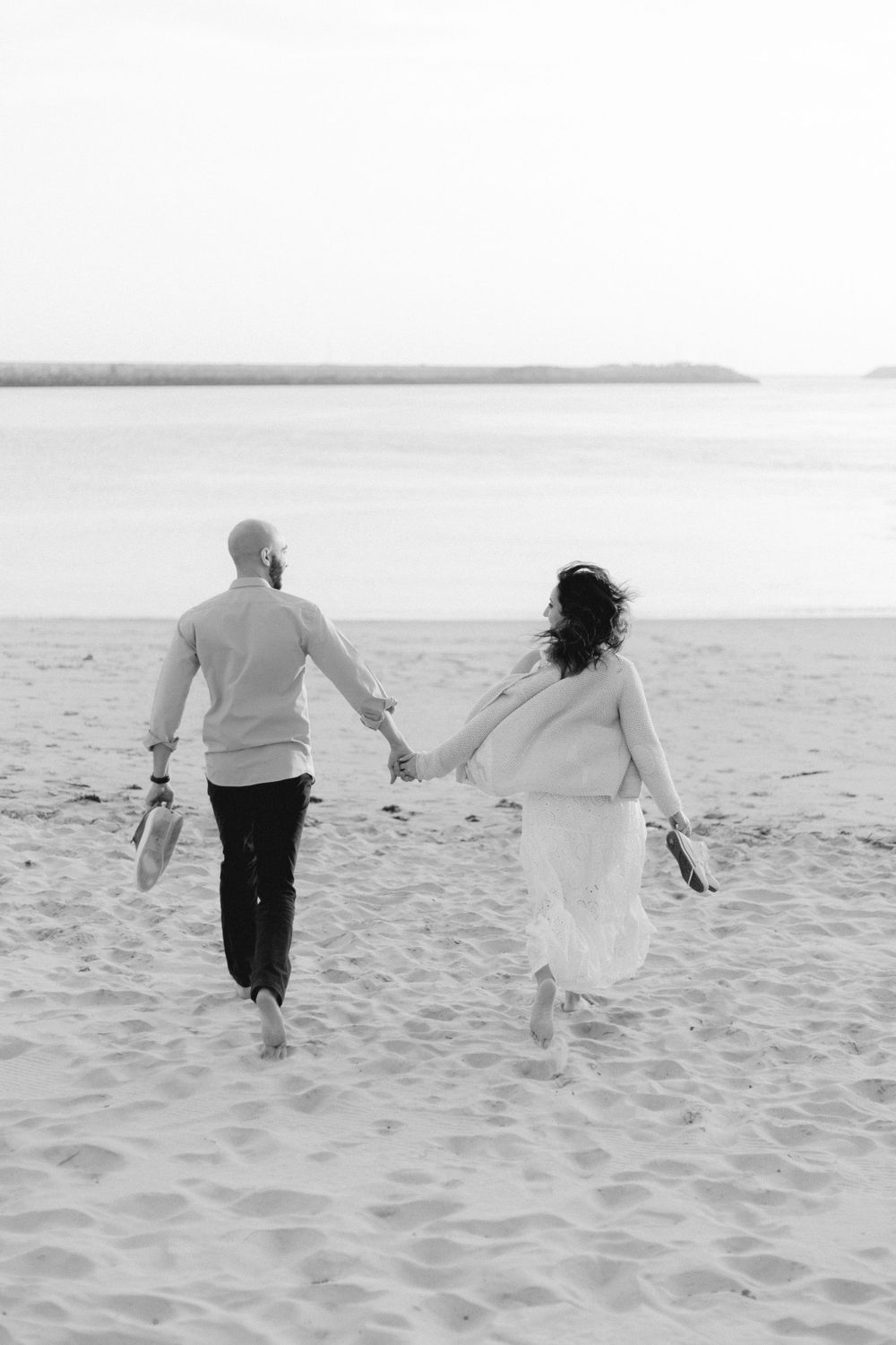 casal a correr em direção ao pôr do sol na praia da barra em aveiro