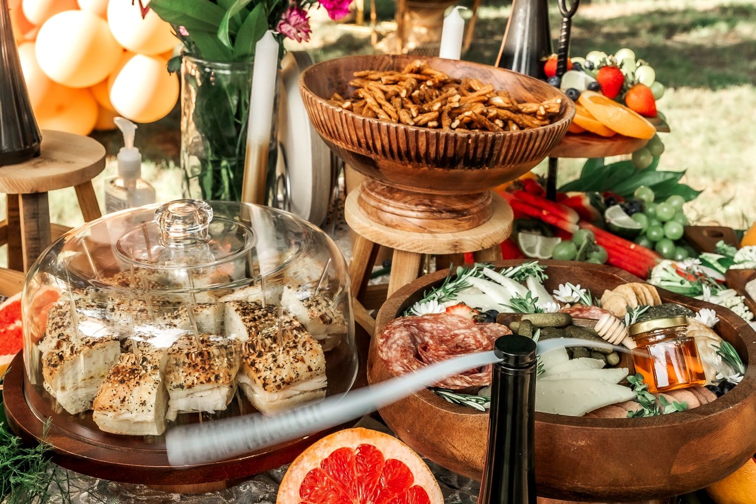 Luxurious grazing table with grapefruit, nuts, and appetizers on wooden serving platters.