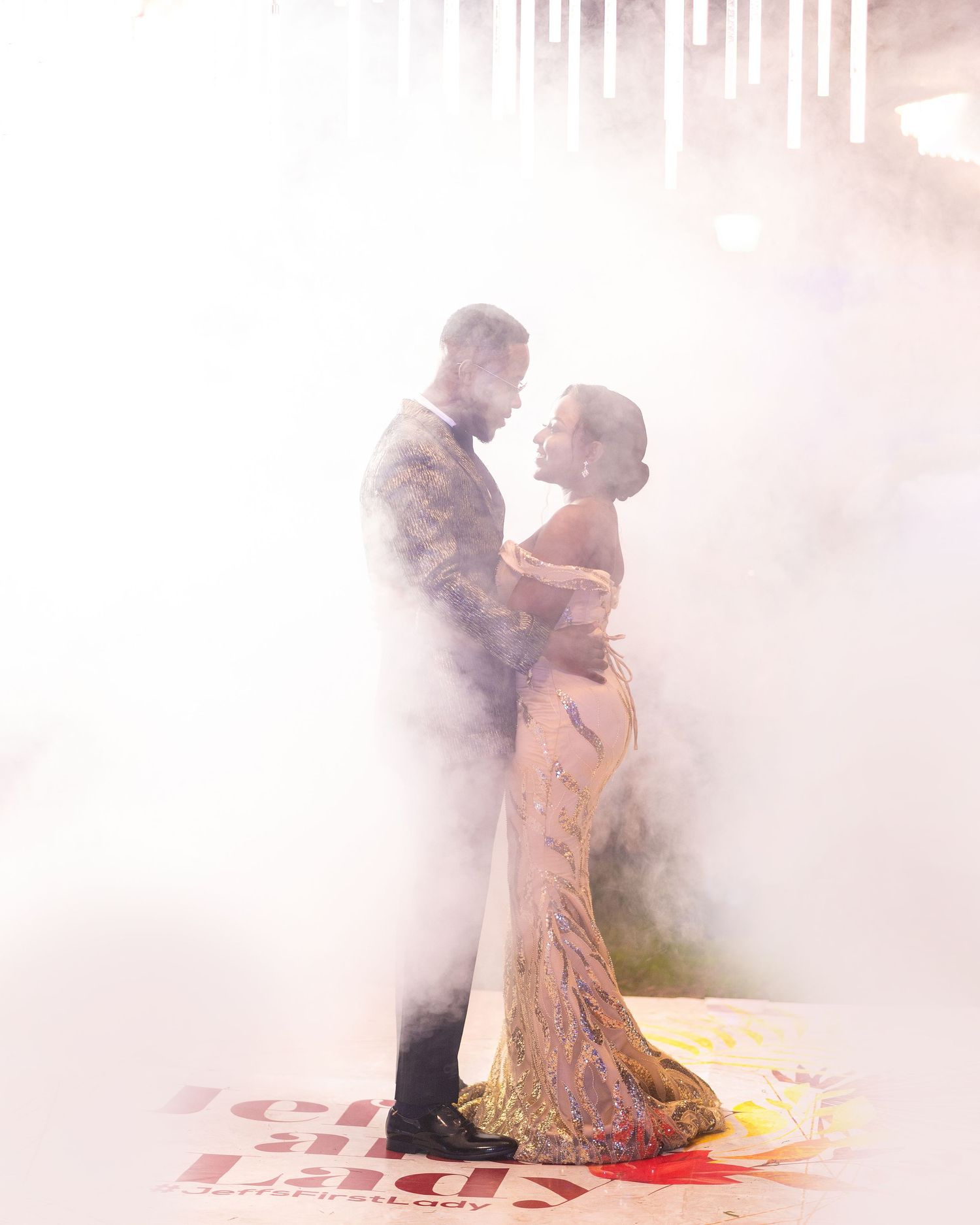 A romantic couple dancing in a dreamy, fog-filled setting with dramatic lighting.