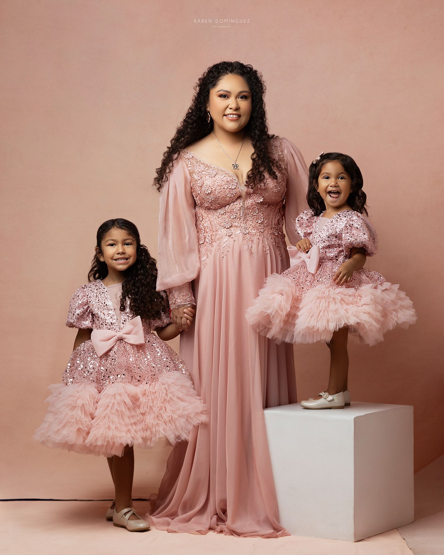 Mother and daughter duo wearing matching pink tulle dresses in a studio portrait session.
