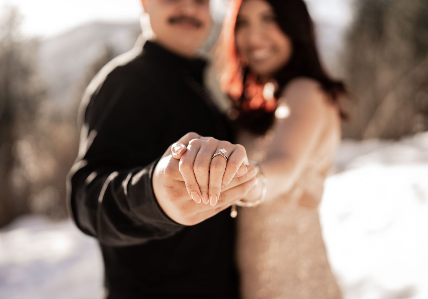 A couple holding hands in a snowy winter setting with a soft focus romantic blur.