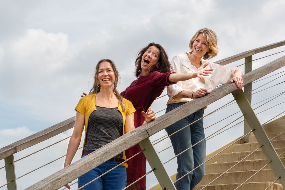 Drie lachende vrouwen samen op een brug – spontane familiefotografie Nijmegen