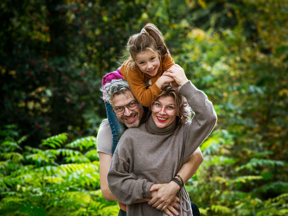Speels familiemoment met kind op de schouders tussen de varens – familieshoot Arnhem