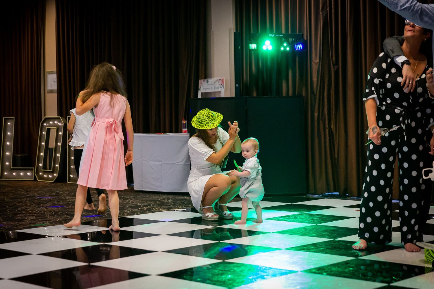 Wedding guest crouches down to dance with a baby at the Crowne Plaza Hotel. Liverpool city centre wedding photography