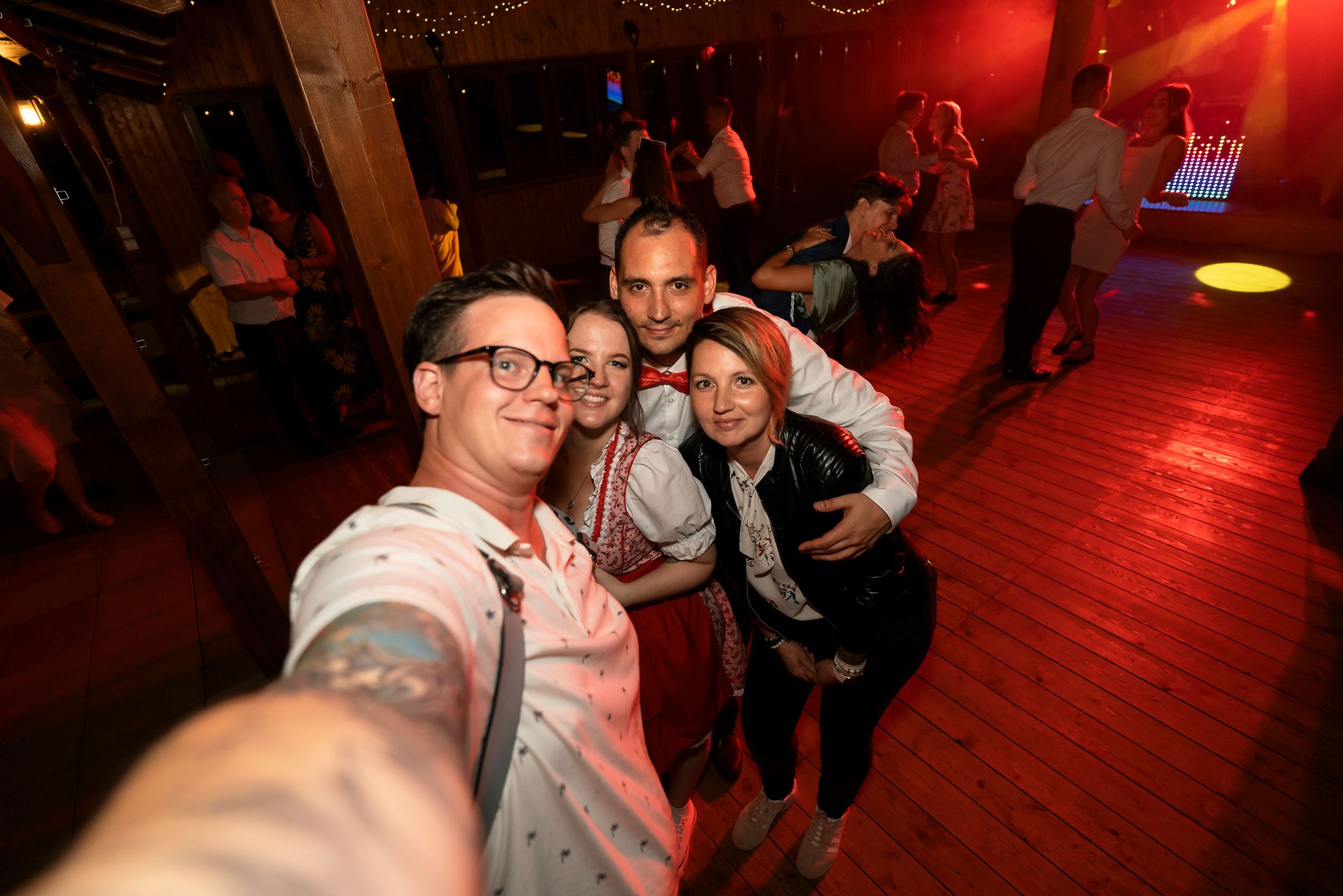 A group takes a selfie in a dimly lit club with red lighting.