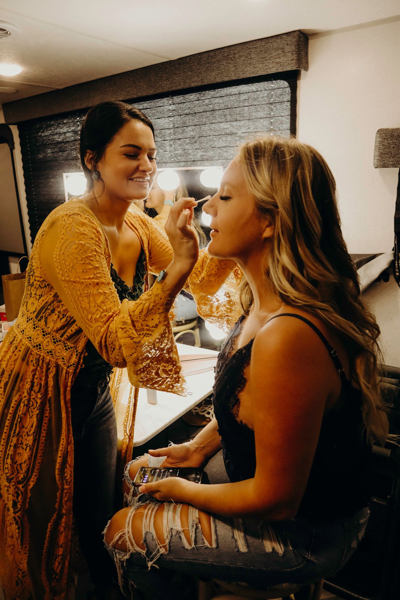 Makeup artist applying cosmetics to a client in a warm-toned setting.