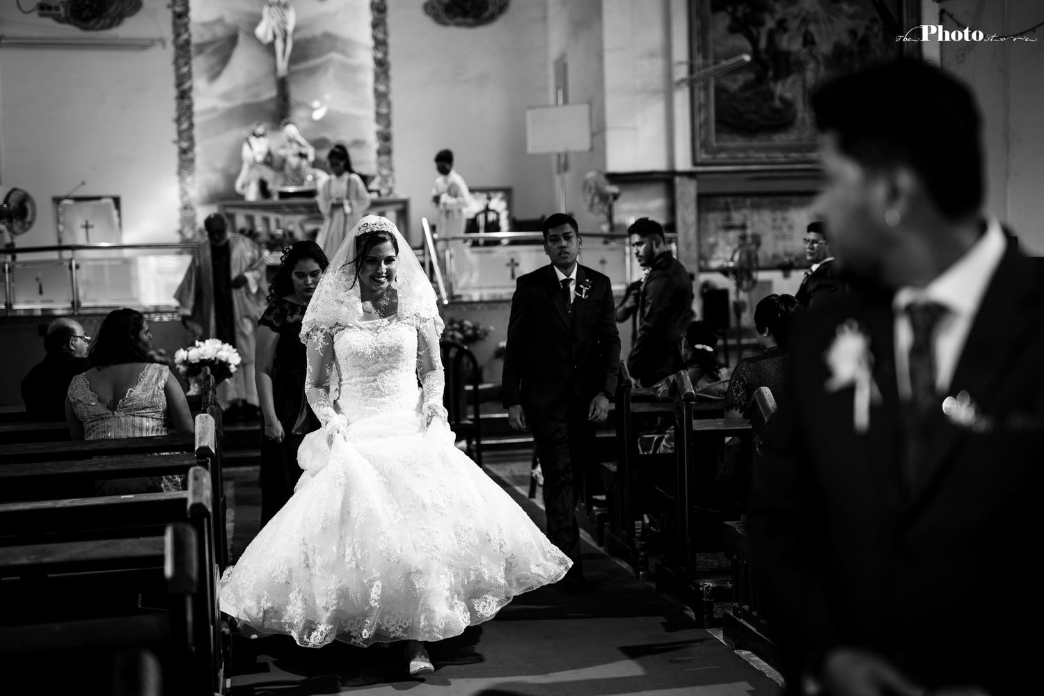 A wedding ceremony captured in black and white showing a couple exchanging vows in a church setting.