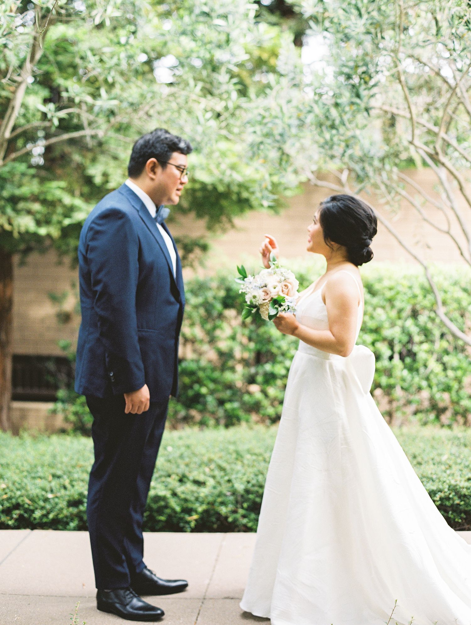 Wedding first look scene with couple standing on garden pathway.