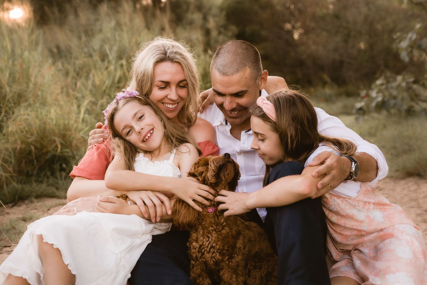 Family cuddling their dog during a Brisbane family photo shoot at the beach
