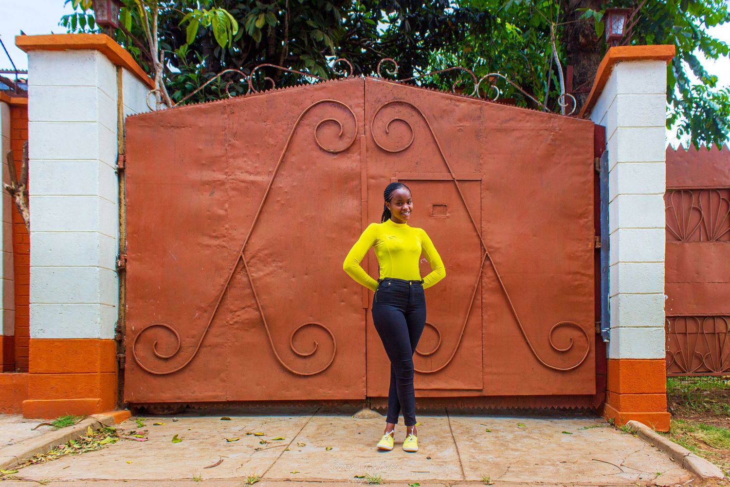 a lady posing (smiling) in front of a gate during a photoshoot