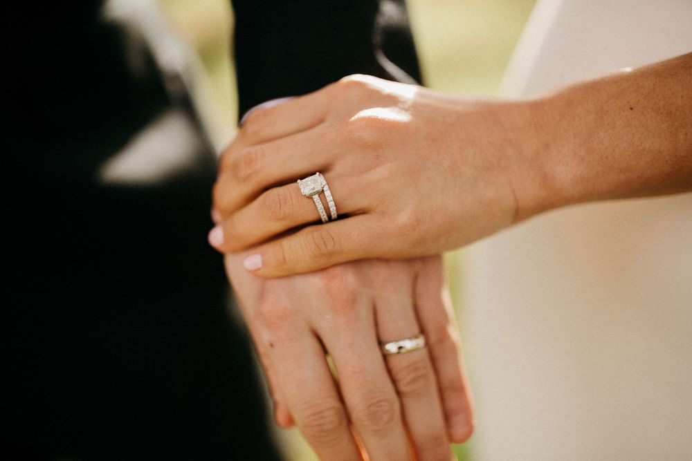 Close-up shot of hands wearing wedding rings against a soft blurred background.